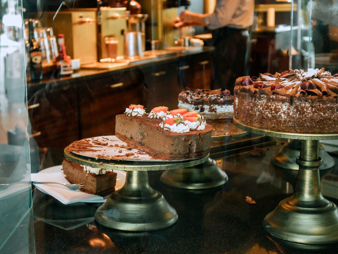 Beautifully finished cakes displayed on stands in a bakery cabinet