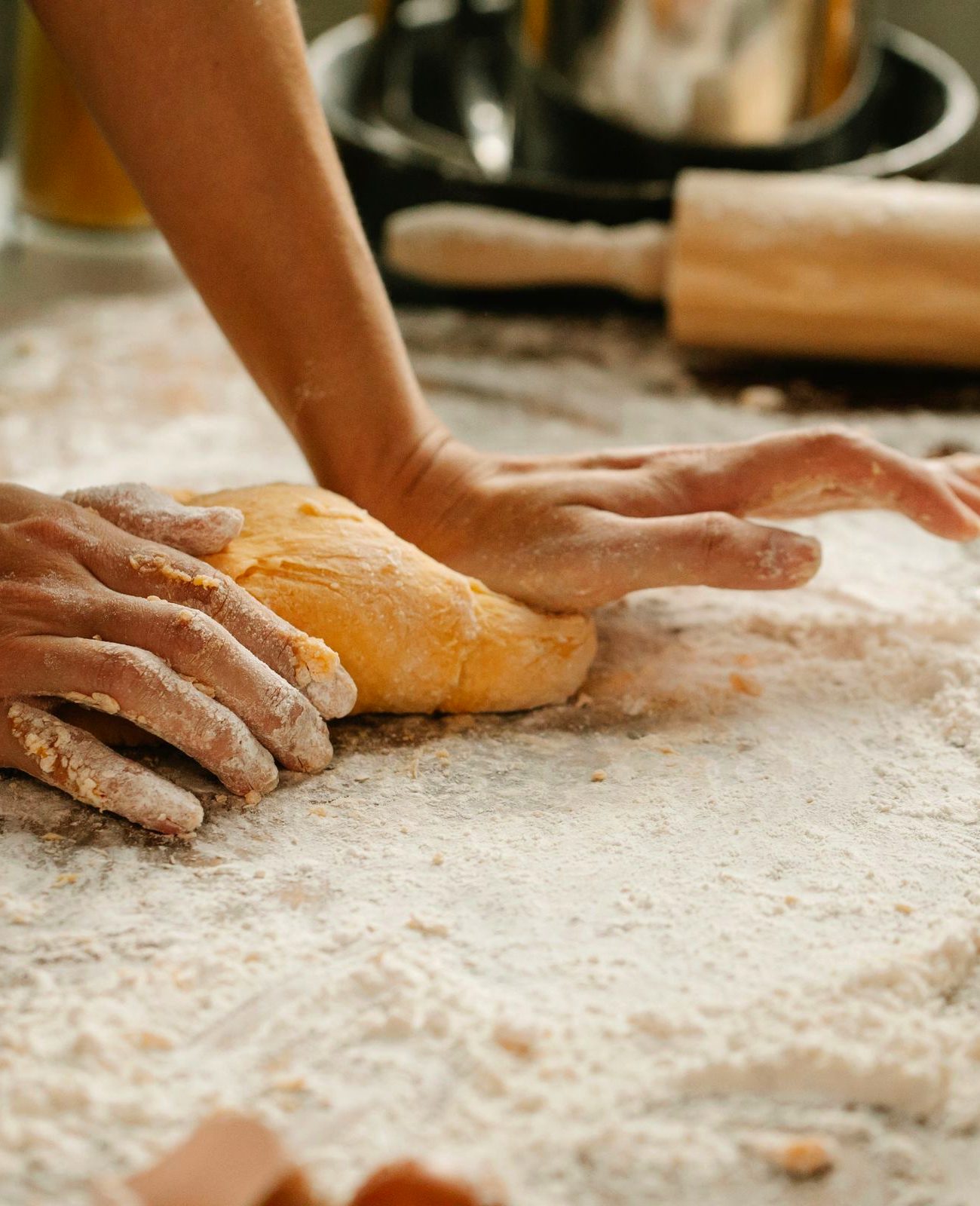 A baker's flour-dusted hands kneading fresh dough on a floured bench